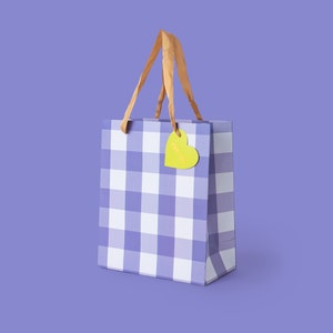 May include: A small gift bag with a purple and white gingham pattern. The bag has tan handles and a yellow heart-shaped tag that says "For You". The background is a solid purple.