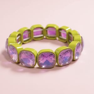 Puede incluir: Una pulsera elástica verde lima con cristales cuadrados iridiscentes morados y rosas. Este accesorio de moda está diseñado para llevarse en la muñeca. Una pieza de joyería elegante.