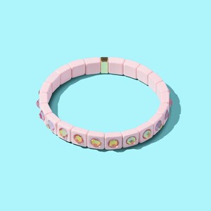 May include: A pink beaded bracelet with iridescent rhinestones. The bracelet is made of square beads and has a gold clasp.