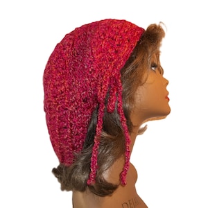 May include: A pink crocheted beanie with long tassels. The beanie is made with a textured stitch and has a gradient of color from light pink to dark pink.