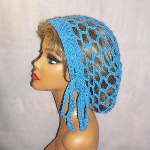 May include: A light blue crocheted hair net with a net-like design. The hair net is tied with a matching blue string. The hair net is displayed on a mannequin head.