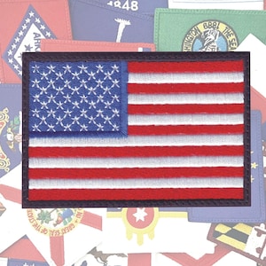 May include: A close-up of an embroidered American flag patch with a dark blue border. The flag is red, white, and blue with 50 white stars on a blue field.