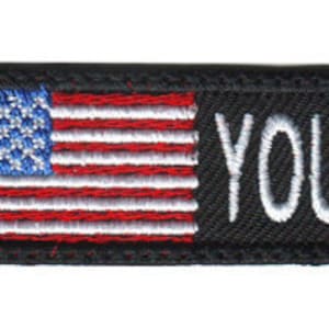 May include: Black embroidered patch with an American flag on the left and the text "YOUR NAME HERE" on the right.