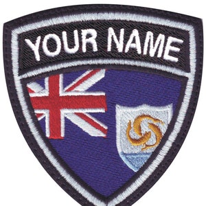 May include: A purple embroidered patch with the flags of the United Kingdom and the British Overseas Territory of Anguilla. The patch has a black border and white stitching. The text "YOUR NAME" is embroidered in white on a black background at the top of the patch.