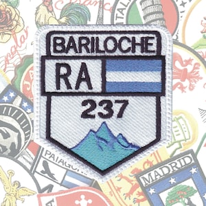 May include: White embroidered patch with blue and black accents. The patch features the text "Bariloche" and "RA 237" along with a blue and white flag and a depiction of mountains.
