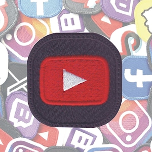 May include: A black and red embroidered patch with a white play button inside a red rectangle. The patch is surrounded by a black border and has a dark purple background.