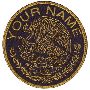 May include: A round, black embroidered patch with a gold outline. The center of the patch features a stylized golden eagle with a serpent in its talons. The eagle is surrounded by a wreath of leaves and the text "YOUR NAME" is embroidered in gold around the edge.
