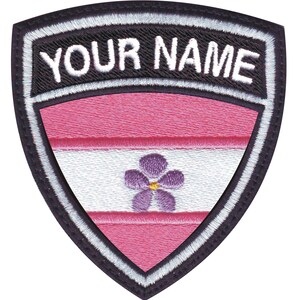 May include: A black and white embroidered patch with a pink, white, and pink striped design and a purple flower with a yellow center. The text "YOUR NAME" is embroidered in white on a black background.