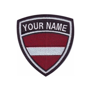 May include: A red and white shield-shaped patch with a black border. The patch has the text "YOUR NAME" in white letters on a black background at the top.