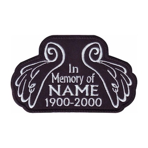 May include: A dark purple patch with white embroidered text and angel wings. The text reads "In Memory of NAME 1900-2000". The patch has a decorative border.