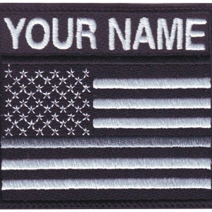 May include: Black and white embroidered patch with the text "YOUR NAME" above a white American flag.