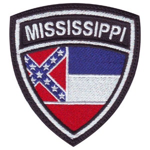 May include: A black and white embroidered patch with the word "MISSISSIPPI" in white lettering. The patch features the state flag of Mississippi, which includes a blue field with a white band and a red and white Confederate battle flag.