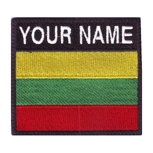 May include: A black and white embroidered patch with the text "YOUR NAME" above a yellow, green, and red horizontal striped flag.