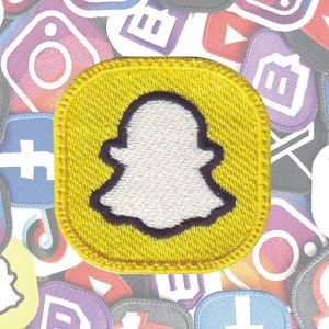 Peut inclure: Patch brodé jaune avec une figure fantomatique blanche au centre. Le fantôme a un contour foncé et a la forme du logo Snapchat.