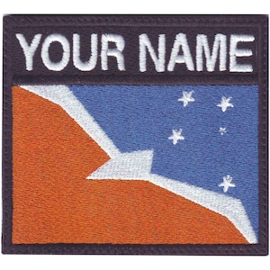 May include: Embroidered patch with a blue and orange flag with white stars and a white bird design. The text "YOUR NAME" is above the flag.