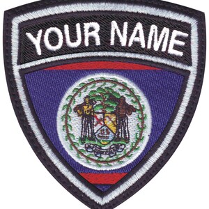 May include: A black and white embroidered patch with a shield shape. The shield features the flag of Belize with a red, white, and blue color scheme. The top of the patch has the text "YOUR NAME" in white letters.