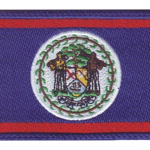 May include: An embroidered patch of the Belize flag. The flag is blue with a red stripe at the top and bottom. The centre of the flag features the national coat of arms, which is a circle with a white background and a green wreath. Inside the wreath is a shield with a red cross and a mahogany tree. The shield is flanked by two men holding axes.