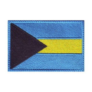 Peut inclure: Un écusson brodé représentant le drapeau des Bahamas. Le drapeau est bleu avec un triangle noir dans le coin supérieur gauche et une bande horizontale jaune au centre.