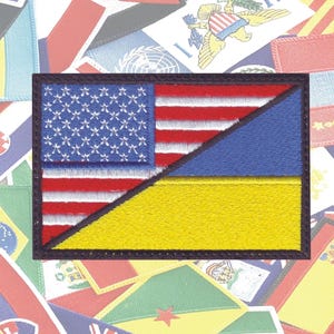 May include: A patch with the American flag and the Ukrainian flag, both sewn together in a diagonal pattern. The American flag is on the top left and the Ukrainian flag is on the bottom right.