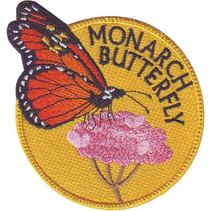 Peut inclure: Un écusson brodé jaune avec un papillon monarque sur une fleur rose. Le texte "MONARCH BUTTERFLY" est écrit autour du bord de l'écusson.