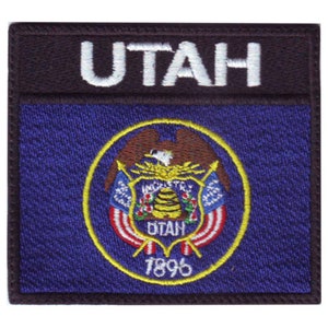 May include: A black and blue embroidered patch with the state seal of Utah. The seal features a bald eagle, a beehive, and the words "Industry" and "Agriculture". The text "Utah" and "1896" are also visible on the patch.