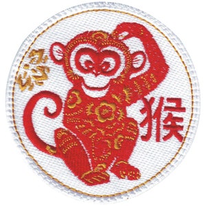 May include: Embroidered patch with a red monkey design and gold detailing on a white background. The patch has Chinese characters and a gold border. The monkey is smiling and holding its head.
