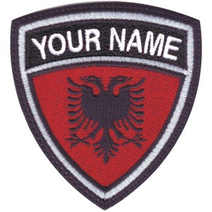May include: A black and white embroidered patch with a red background. The patch features a black double-headed eagle and the text "YOUR NAME" in white.