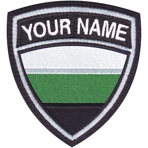 May include: A black, white, and green embroidered patch with a white border and the text "YOUR NAME" in white lettering.
