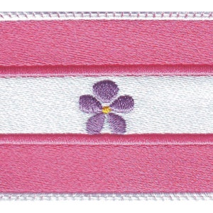 May include: A pink and white embroidered patch with a purple flower in the centre. The flower has a yellow centre.
