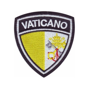 May include: A black and white embroidered patch with the word "VATICANO" in white lettering. The patch features a yellow and white shield with a papal coat of arms.