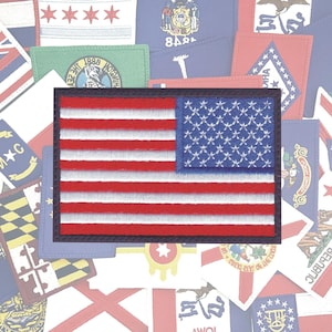 May include: A close-up of an embroidered American flag patch with red and white stripes and a field of blue stars. The patch is surrounded by other patches of various designs.