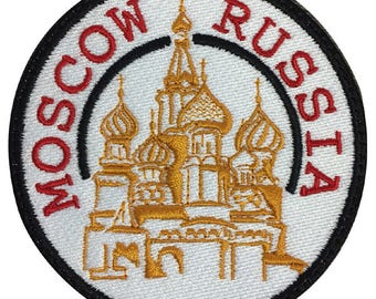 May include: A white embroidered patch with a black border. The patch features a gold outline of St. Basil's Cathedral in Moscow, Russia. The words "Moscow" and "Russia" are written in red around the cathedral.