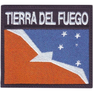 May include: A black and white embroidered patch with the text "TIERRA DEL FUEGO" in white lettering. The patch features a blue and orange flag with a white star design.