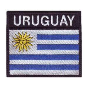 May include: Embroidered patch featuring the flag of Uruguay. The flag is blue and white with a yellow sun in the upper left corner. The word "URUGUAY" is embroidered in white on a black background above the flag.
