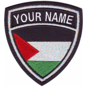May include: A black, white, red and green embroidered patch in the shape of a shield with a white border. The patch features the Palestinian flag and the text "YOUR NAME" in white.