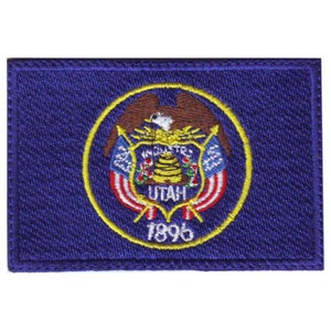 May include: A blue embroidered patch with the state seal of Utah. The seal features a bald eagle with outstretched wings, a beehive, and the words "Industry" and "Agriculture". The seal is surrounded by a yellow circle with the words "Utah" and "1896".
