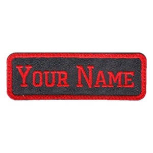May include: Black rectangular patch with red stitching around the edges. The text "YOUR NAME" is embroidered in red.