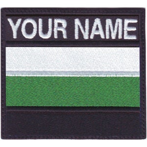 May include: Black and white embroidered patch with the text "YOUR NAME" at the top, a white stripe, a green stripe, and a black stripe at the bottom.