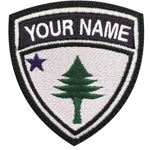 May include: A white and black embroidered patch with a green pine tree and a blue star. The text "YOUR NAME" is embroidered in white on a black background.