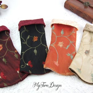 Könnte beinhalten: Vier Stoffbeutel mit gestickten Blumenmustern. Die Beutel sind in Burgunderrot, Schwarz, Orange und Beige.
