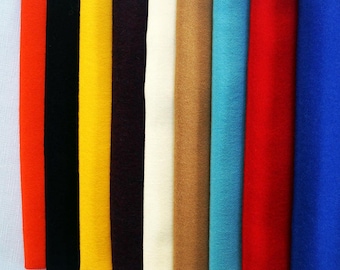 May include: Ten different colored cashmere scarves with fringed edges. The scarves are arranged in a row, with the blue scarf at the end of the row. The blue scarf has a white label with the text "Alena Designs" on it.