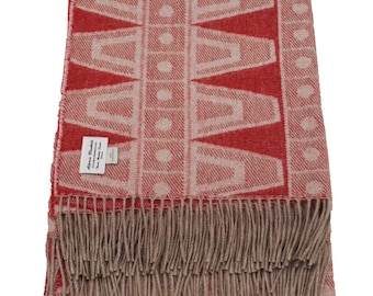 May include: A red and beige patterned blanket with a geometric design. The blanket has a fringe along the bottom edge and a tag in the corner. The pattern consists of red shapes and white dots on a beige background.