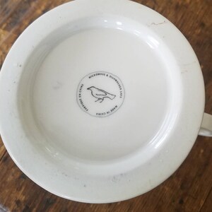 May include: White ceramic mug with a black bird illustration and the text "Microwave & Dishwasher Safe. Made in China. Fabriqu&eacute; en Chine" on the bottom.