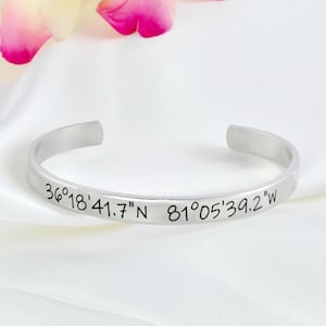 May include: A silver bangle bracelet with the coordinates "36°18'41.7"N 81°05'39.2"W" engraved on it.