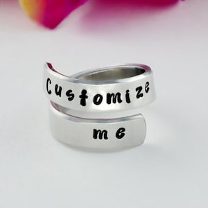 May include: A silver ring with the words "Customize me" engraved on it.