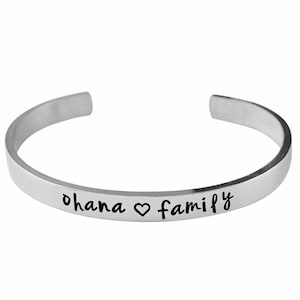 May include: Silver bangle bracelet with the inscription "ohana heart family".