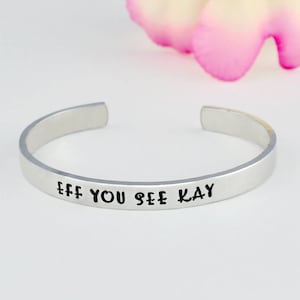 May include: Silver bracelet with the text "Eff You See Kay" engraved on it.