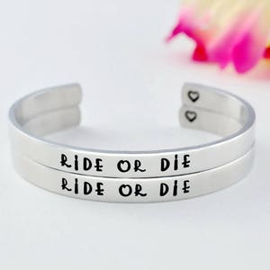 May include: Silver double bangle bracelet with the words "Ride or Die" engraved on each band.