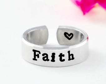 May include: A silver adjustable ring with the word "Faith" engraved on the band. A small heart is engraved on the inside of the ring.