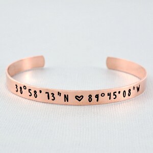 May include: A copper cuff bracelet with the coordinates "38° 58' 73" N ♥ 89° 45' 08" W" engraved on it.